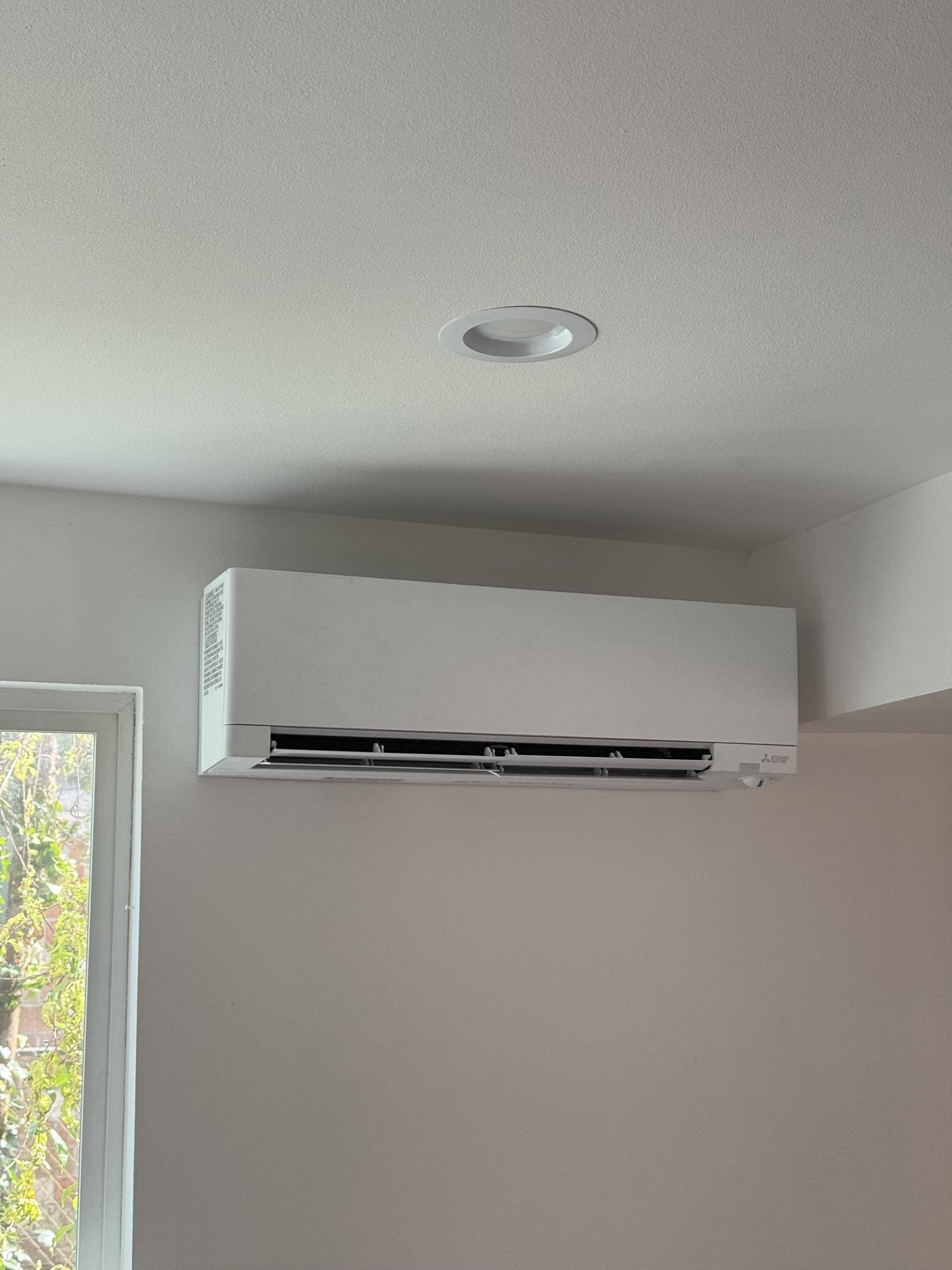 Ductless mini-split indoor unit mounted high on a living room wall
